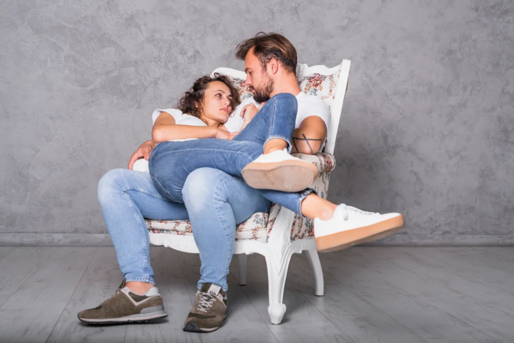 Um casal numa cadeira abraçados conversando com linguagem aberta e com carinhos